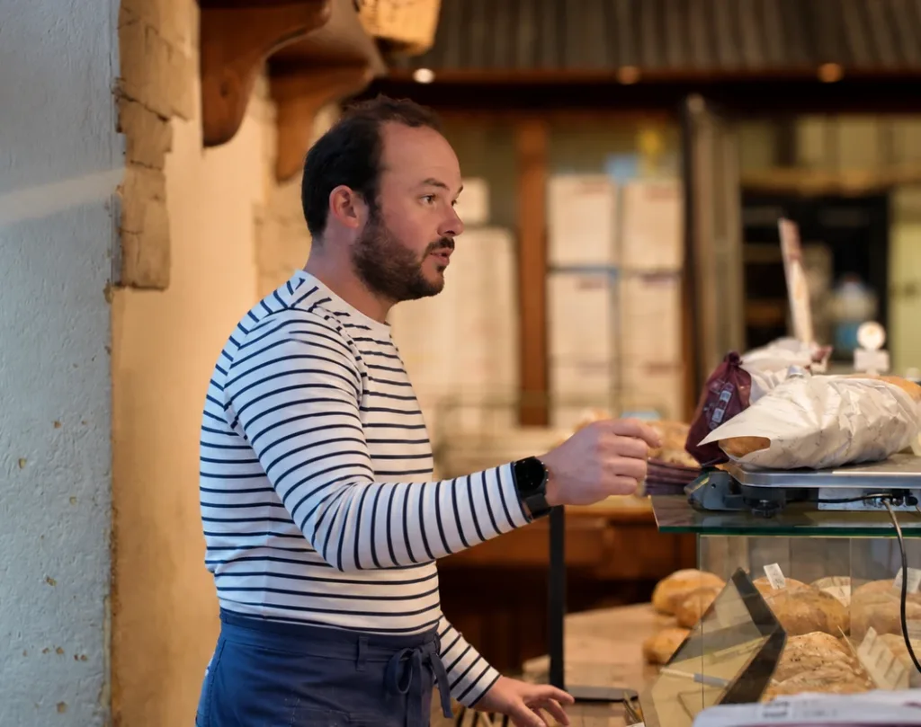 Amaury Cavé au comptoir d'une boutique Mariette, devant les pains en vitrine