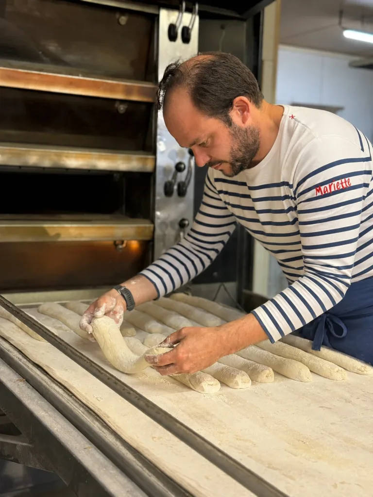 Amaury Cavé, en marinière Mariette, façonne des pâtons de baguettes devant le four